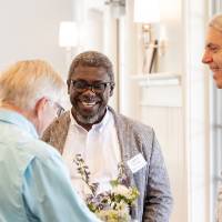 Adebayo Ogundipe standing around table with two other gentleman at event with big smile on his face